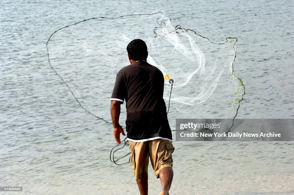 Danny Shivnandan catches mullets in hi fishing net at Coney