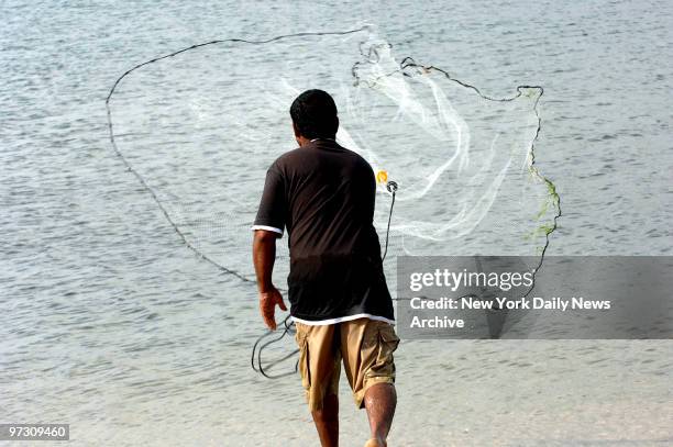 Danny Shivnandan catches mullets in hi fishing net at Coney Island creek, Neptune Ave.