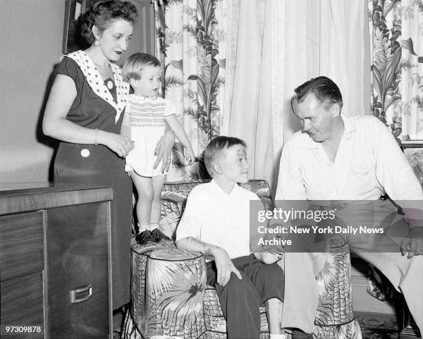 Gerard Muller, his mother and sister, Barbara look on happily as Fireman Bernard Curran clasps hand of the 11-year-old boy, at 923 Simpson St., Bronx...