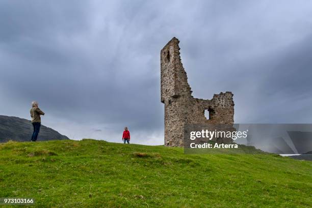 Elderly tourists visiting 16th century Ardvreck Castle ruin at Loch Assynt in the Scottish Highlands, Sutherland, Scotland, UK.
