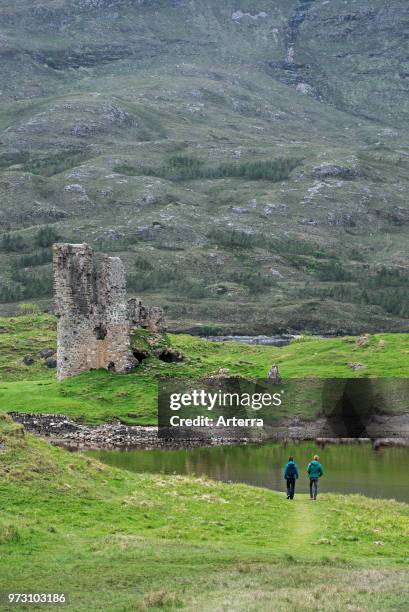 Tourists visiting 16th century Ardvreck Castle ruin at Loch Assynt in the Scottish Highlands, Sutherland, Scotland, UK.