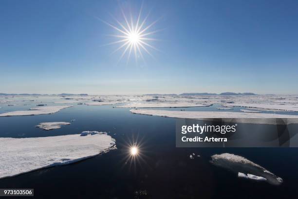 Midnight sun over the Arctic Ocean with drifting ice floes, north of the Arctic Circle at Nordaustlandet, Svalbard / Spitsbergen, Norway.