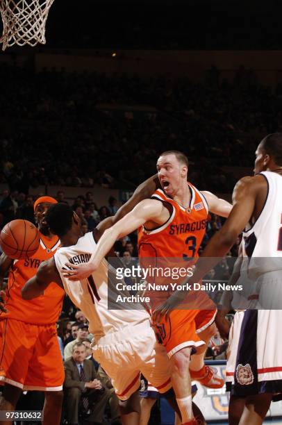 Gerry McNamara of the Syracuse University Orangemen passes the ball as he's defended by University of Connecticut Huskies' Hilton Armstrong during...