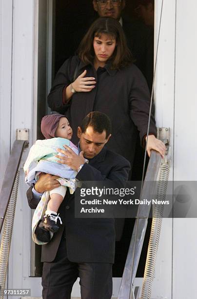 Juan Miguel Gonzalez caries his 6-month-old son, Hianny, as he leaves plane at Dulles International Airport followed by his wife, Nercy Carmenate...