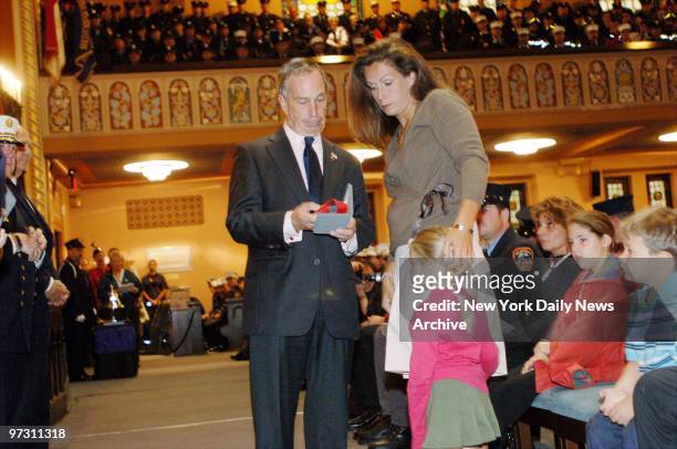Mayor Michael Bloomberg presents a medal to Eileen Bellew, widow of Lt. John G. Bellew, and her daughter, Katreana, during a ceremony honoring FDNY...