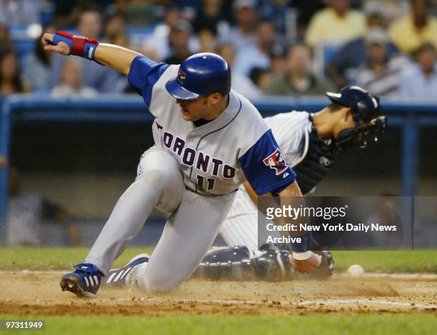 Toronto Blue Jays' Eric Hinske scores in the fourth inning as New York Yankees' catcher Jorge Posada tries to field the throw home. The Blue Jays...