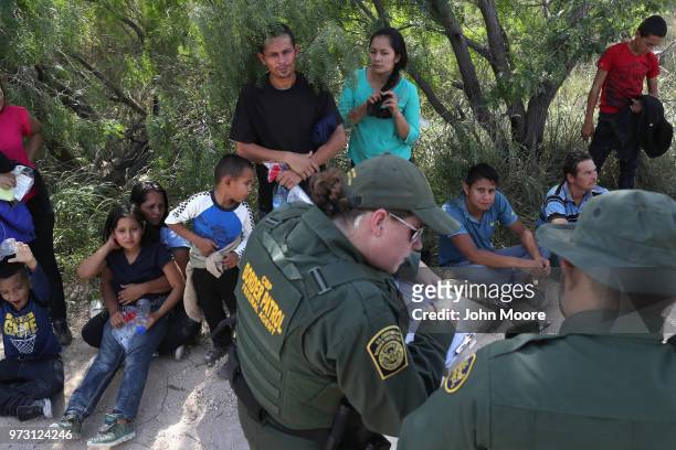 Central American asylum seekers wait as U.S. Border Patrol agents take groups of them into custody on June 12, 2018 near McAllen, Texas. The families...