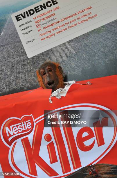 Member of the environmental action group Greenpeace wearing an orangutan mask takes part in an anti-deforestration rally while holding a 'Kit Kat'...