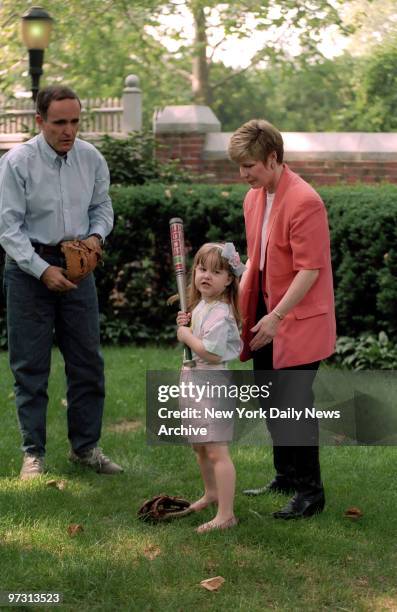 Mayor Rudolph Giuliani, the city's First Yankee Fan, dons a catcher's mitt as he and wife Donna Hanover give daughter Caroline a lesson in the fine...