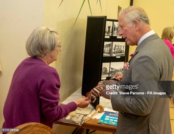 The Prince of Wales receives a woollen vikings slash from June Cochrane during a visit to the Owenkillew Community Centre in Gortin, as part of his...