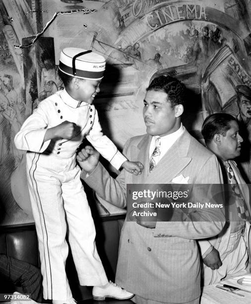 Day after Joe Louis versus Max Schmeling II fight., Page Boy Frand Brown raises his tiny fists against the Bomber's mighty maulers and dares champ to...