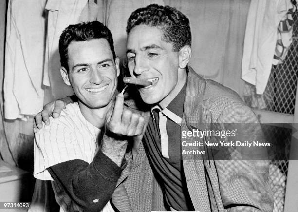 New York Yankees' shortstop Phil Rizutto gets a light from second baseman Jerry Coleman in the clubhouse at Yankee Stadium. Coleman's wife gave birth...