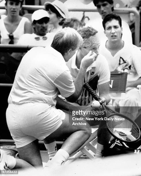 Trainer Bill Norris checks John McEnroe's right eye after he was hit by a tennis ball during his second-round victory over David Engel.