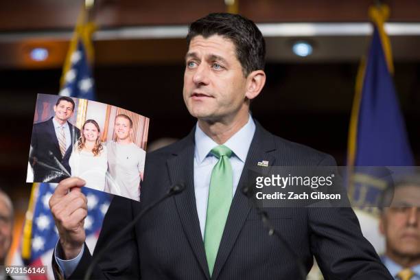 House Speaker Paul Ryan holds up a photograph of himself with people in his district who have been affected by the opioid epidemic during a news...