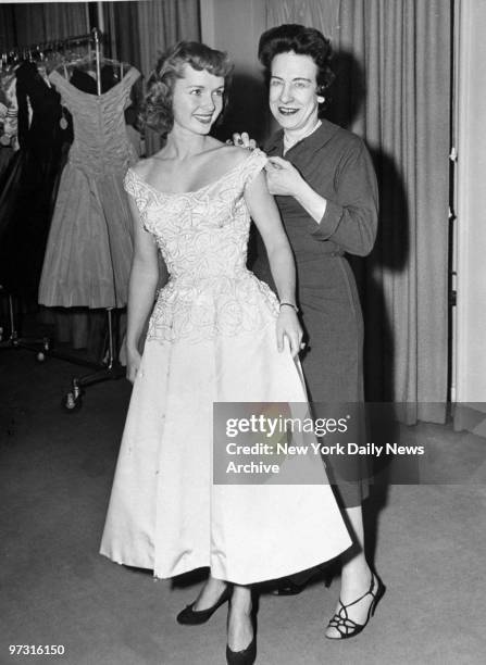 Debbie Reynolds tries on a wedding dress with the help of designer Ceil Chapman.