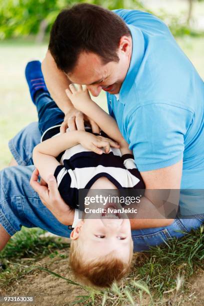 father tickling his son in nature - ivanjekic stock pictures, royalty-free photos & images