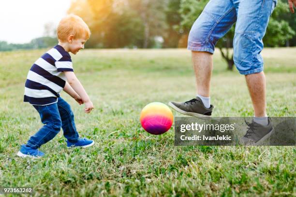 father and son playing football in nature - ivan jekic stock pictures, royalty-free photos & images