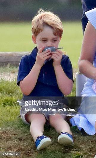 Prince George of Cambridge plays with a toy walkie talkie as he attends the Maserati Royal Charity Polo Trophy at the Beaufort Polo Club on June 10,...