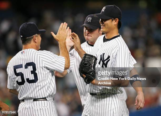 New York Yankees' third base coach Larry Bowa celebrates with first baseman Jason Giambi and starter Chien-Ming Wang after Wang pitched a complete...