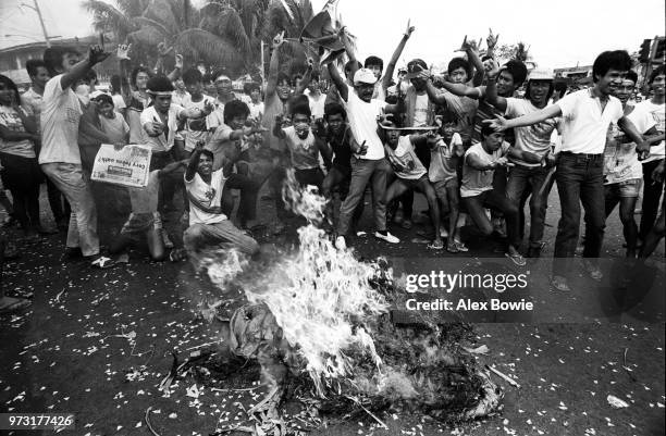 Enthusiastic supporters of opposition leader Cory Aquino burn an effigy of Marcos in the streets leading to Malacanang Palace, home of President...