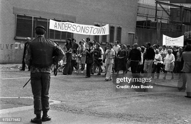 Under the watchful eye of a British soldier, thousands of Catholic women and some men from the Catholic Falls Road and Andersonstown estate walk past...