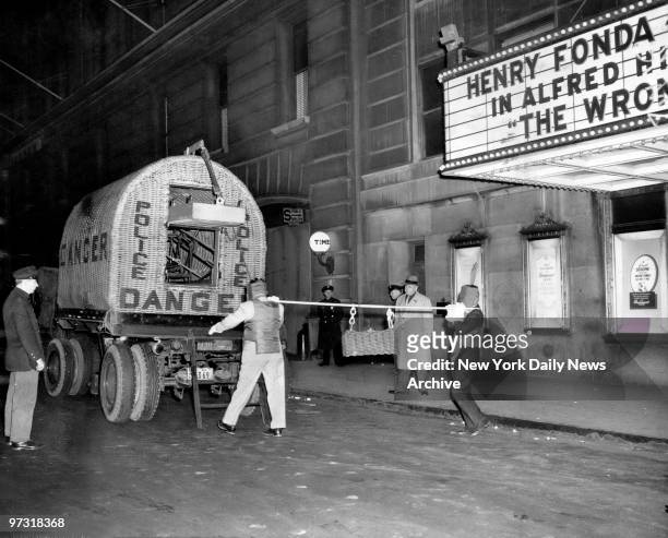 Members of the bomb squad haul a mesh iron sealer containing a bomb from the Paramount theater's side entrance to the truck which will go to Fort...