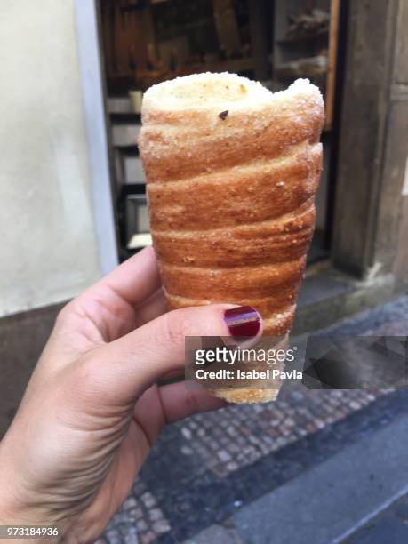 woman eating trdelnik in prague, czech republic - isabel pavia stockfoto's en -beelden