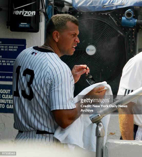 New York Yankees' third baseman Alex Rodriguez cools off in front of a giant fan in the dugout on a scorching August afternoon during a game against...