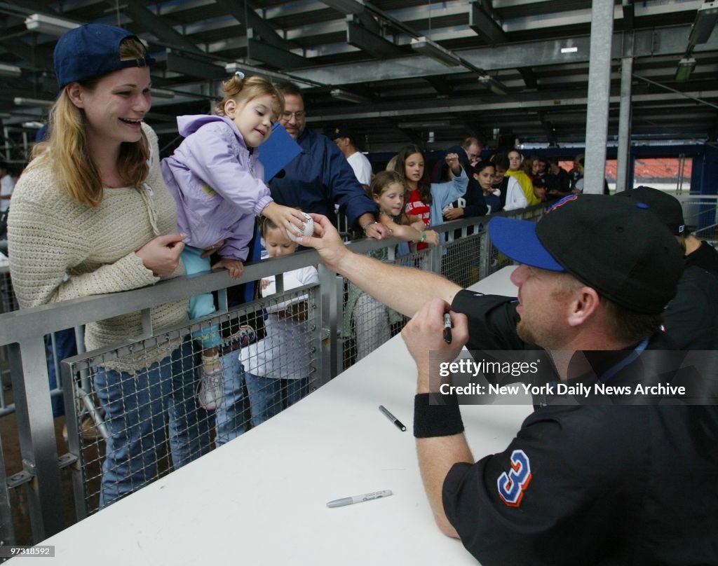 New York Mets' catcher Vance Wilson autographs a baseball fo