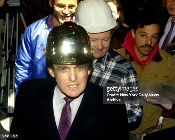 Donald Trump wearing a gold hard hat given to him by construction workers at the Trump Palace.