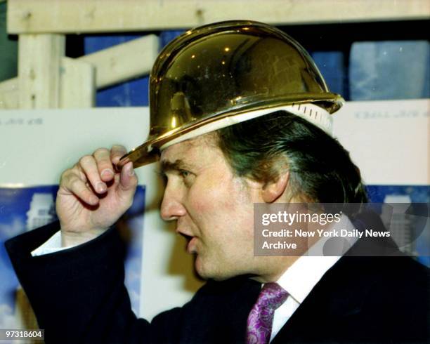 Donald Trump wearing a gold hard hat given to him by construction workers at the Trump Palace.