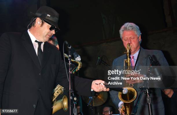 Gracious Blues Brother Dan Aykroyd holds the microphone as former President Bill Clinton plays his saxophone during a celebration of the Mohegan Sun...