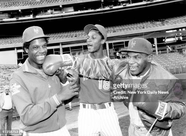 New York Mets' Dwight Gooden laughs off a right from heavyweight Mike Tyson as referee Darryl Strawberry supervises the event at Shea Stadium.