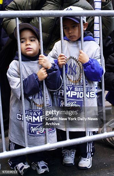 Two tiny fans cheer on their team as floats carrying the World Champion New York Yankees move up Broadway through the Canyon of Heroes during a...