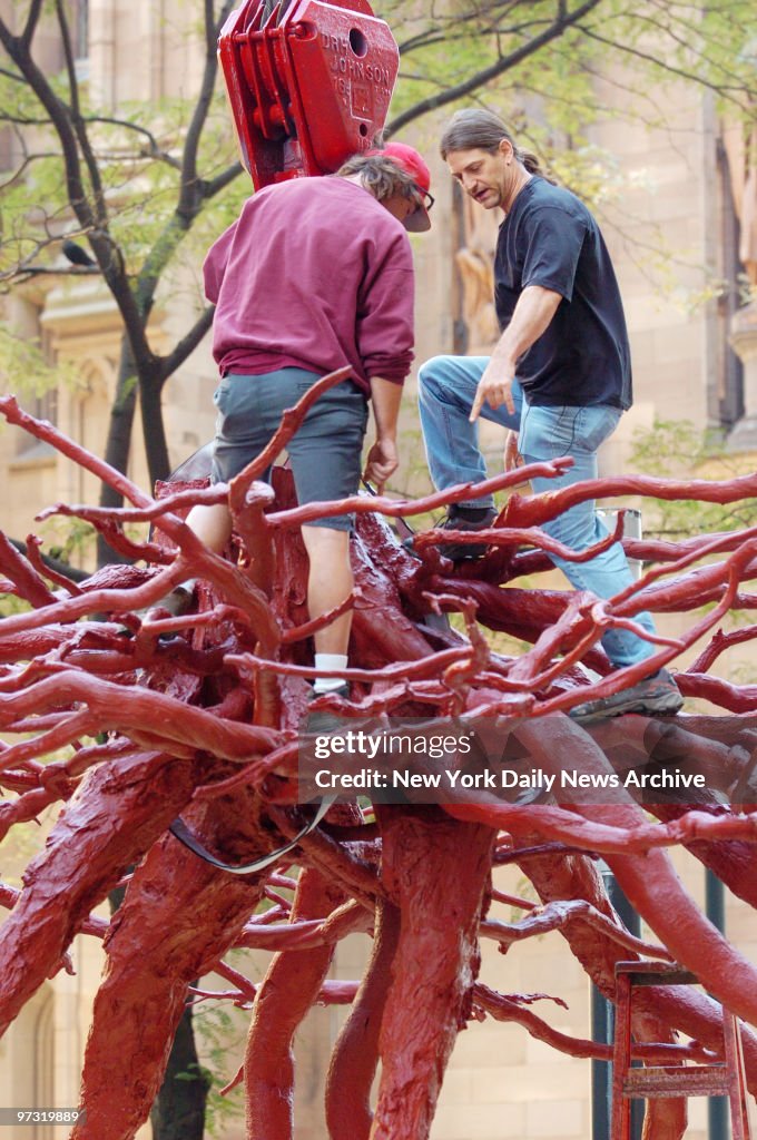 Steve Tobin (right) stands atop his sculpture, "The Trinity