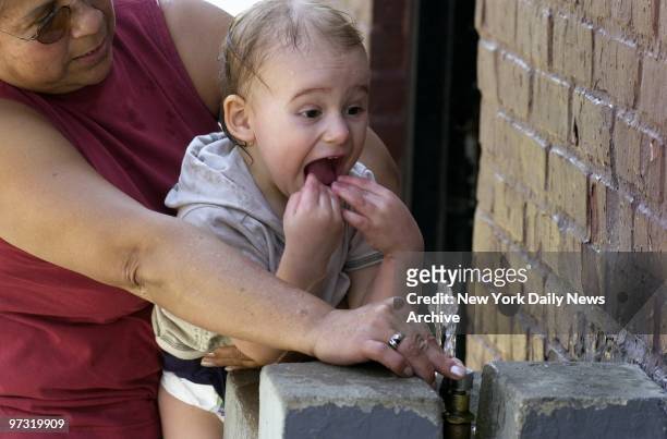 Grandmother helps tot take her first-ever drink from a water fountain on a balmy, 80-degree afternoon at Juniper Valley Park in Middle Village,...