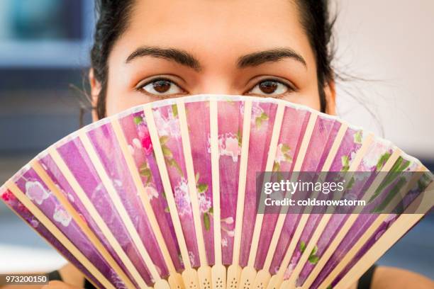 young woman holding asian folding fan in front of face - folding fan stock pictures, royalty-free photos & images