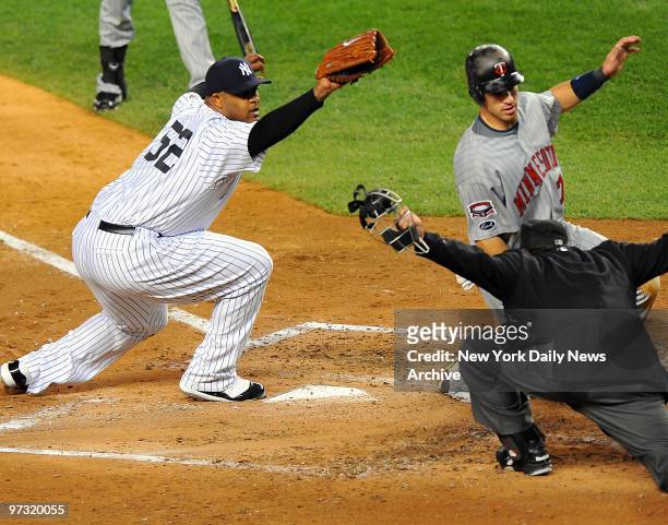 Minnesota Twins catcher Joe Mauer is safe at home scoring on a passed ball by New York Yankees catcher Jorge Posada in the third inning as New York...