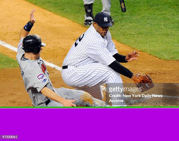 Minnesota Twins catcher Joe Mauer is safe at home scoring on a passed ball by New York Yankees catcher Jorge Posada in the third inning as New York...