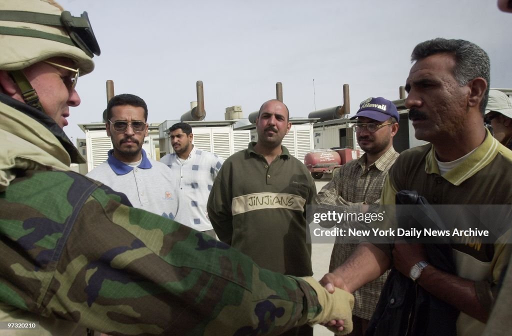 U.S. Navy Rear Adm. Charles Kubic (left) greets Iraqi worker