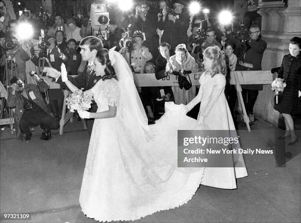 Julie and David Eisenhower leave Marble Collegiate Church after their wedding. Tricia Nixon, Bridesmaid, holds the train of Julie's wedding gown.