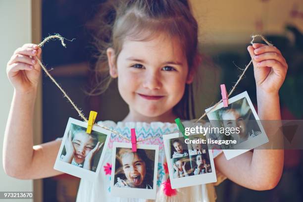 vier jahre alten mädchen halten zeichenfolge der sofortbilder - clothes peg stock-fotos und bilder