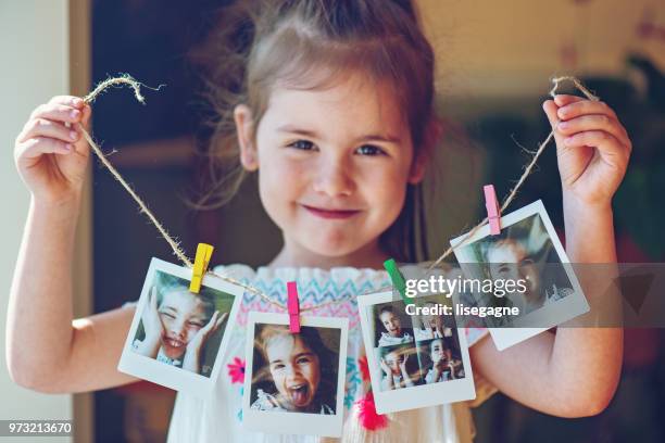 four years old little girl holding string of instant photos - clothes peg stock pictures, royalty-free photos & images