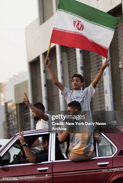 Men fly the Iranian flag in southern Beirut, Lebanon, as they celebrate on the second day of a ceasefire between Israel and Hezbollah.
