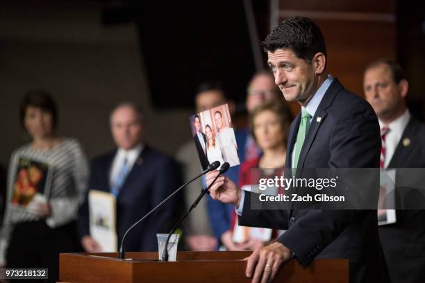 House Speaker Paul Ryan holds up a photograph of himself with people in his district who have been affected by the opioid epidemic during a news...