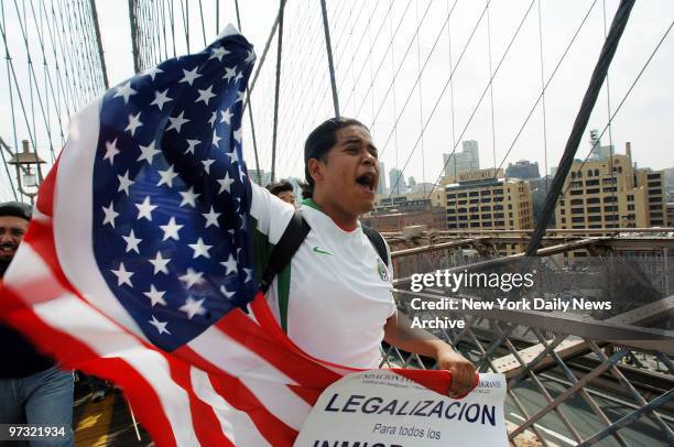 Demonstrator waves an American flag as thousands of legal and undocumented immigrants - and their supporters - stream over the Brooklyn Bridge during...