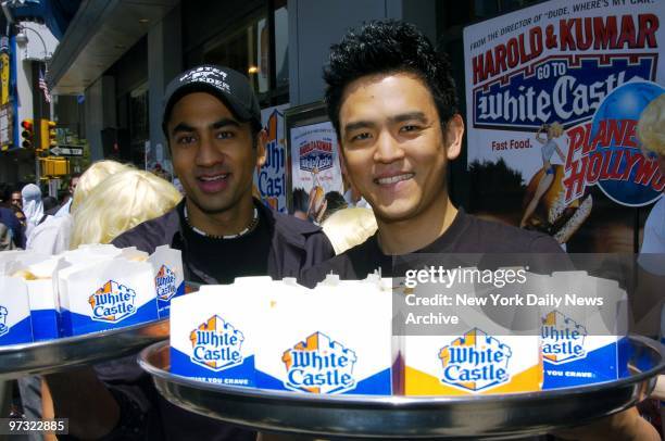 Kal Penn and John Cho offer White Castle hamburgers to passersby outside Planet Hollywood in Times Square. They were present for a screening of their...