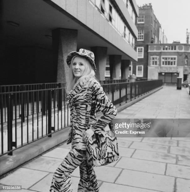 English singer Janie Jones, wearing a tiger print suit with matching shoulder bag and hat, stands outside court in occasion of a hearing on her...