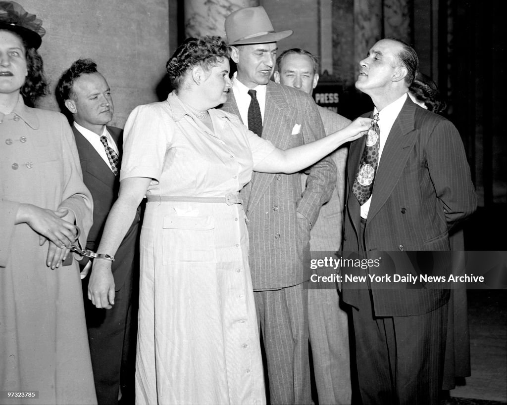 Handcuffed to a policewoman, Martha Beck reaches to adjust t