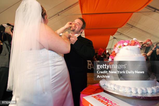 Newlyweds John Townsend and Michele Sarao eat wedding cake after their marriage ceremony in a tent behind the Dunkin' Donuts in Hackensack, N.J. The...